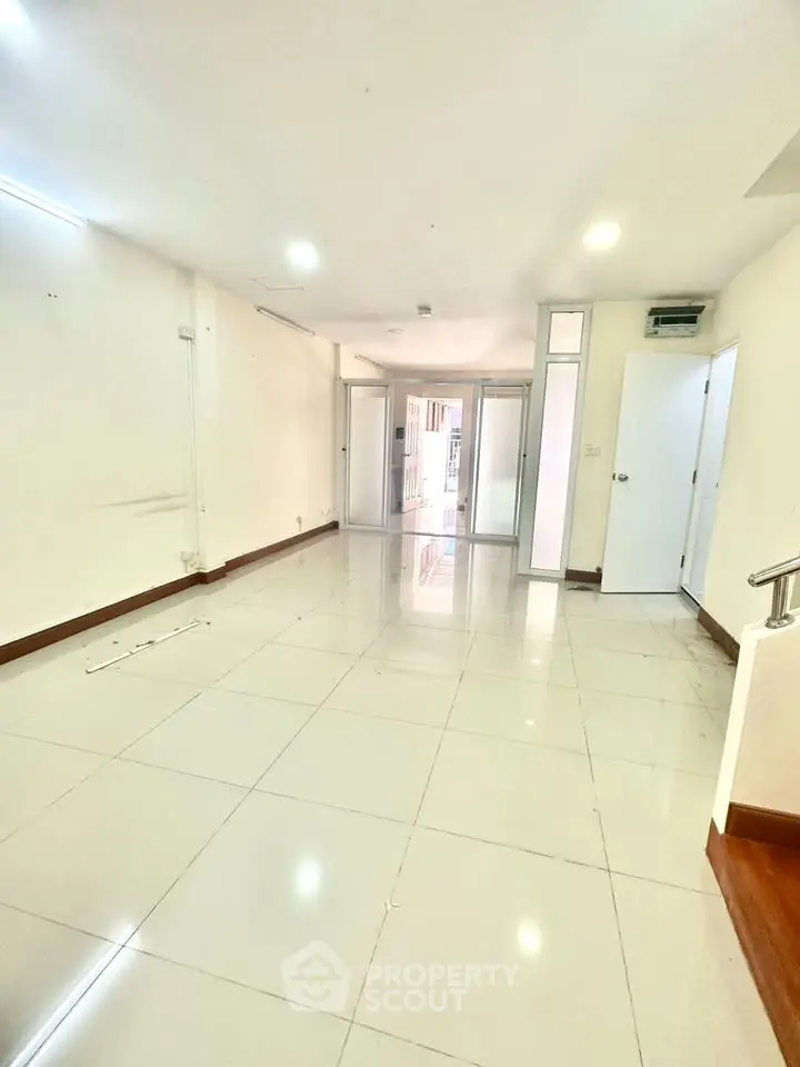 Spacious empty room with glossy tiled flooring and bright lighting, ideal for customization.