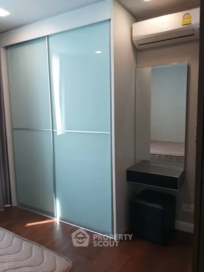 Modern bedroom with sliding closet doors and air conditioning unit.