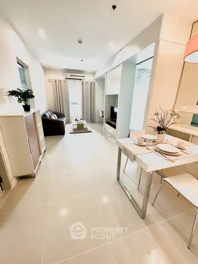 Modern open-plan living room with dining area, featuring sleek furniture and bright natural lighting.