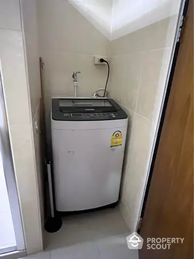 Compact laundry area with modern washing machine in tiled corner space