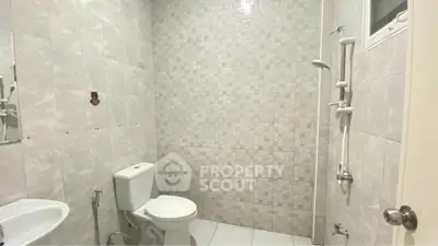 Modern bathroom with tiled walls and white fixtures in a real estate property.