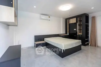 Modern minimalist bedroom with sleek black furniture and ample storage space.