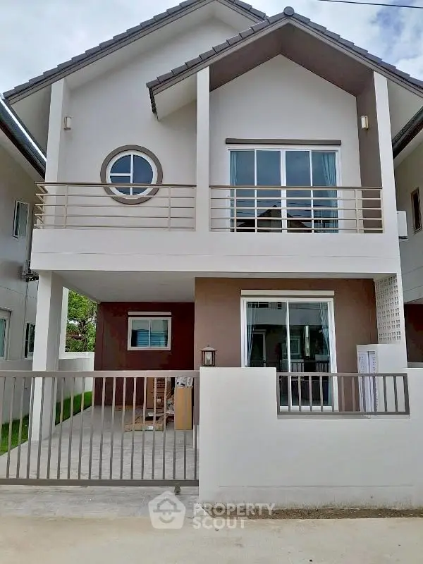 Modern two-story house with balcony and gated entrance, showcasing contemporary architecture and spacious design.