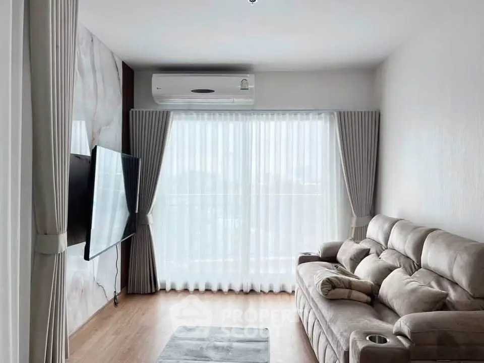 Modern living room with plush sofa and wall-mounted TV, featuring elegant curtains and air conditioning.