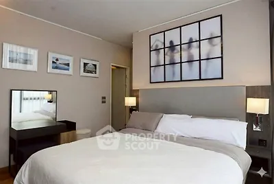 Modern bedroom with stylish decor and wall art, featuring a cozy bed and elegant lighting.