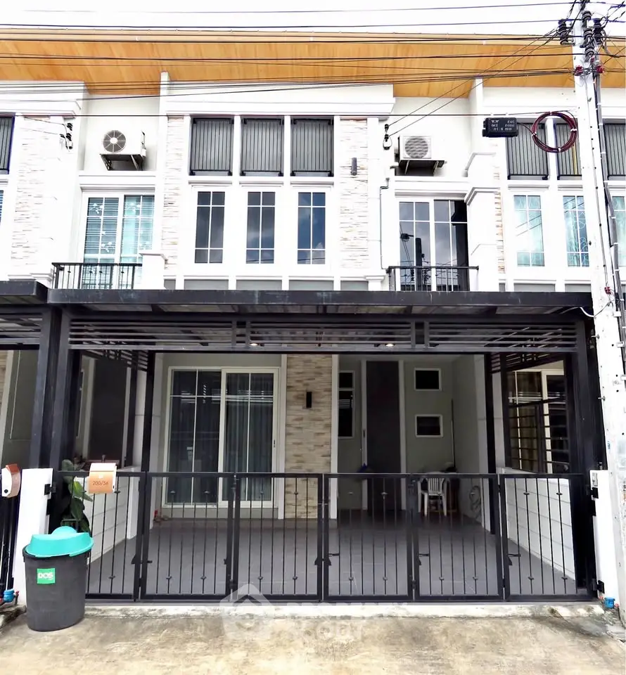 Modern townhouse exterior with gated entrance and balcony