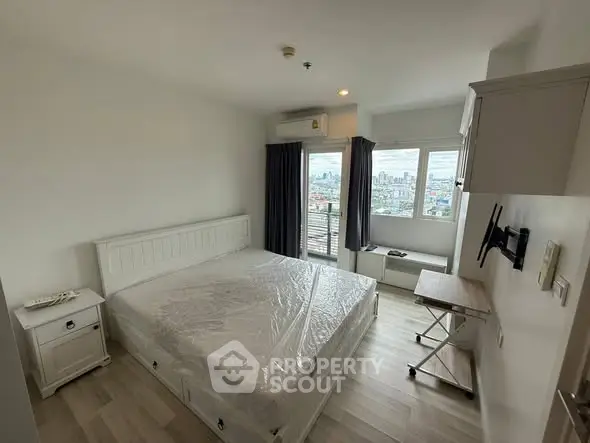 Modern bedroom with city view, featuring a large bed and wall-mounted TV.