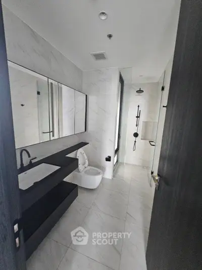 Modern bathroom with sleek black fixtures and large mirror in luxury apartment.