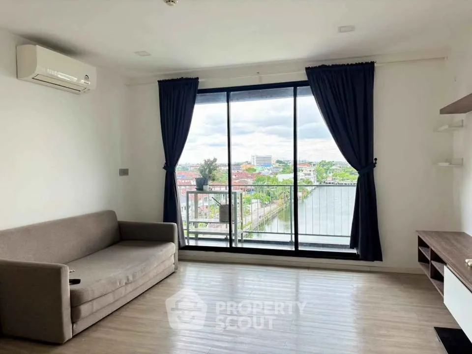 Spacious living room with large window offering stunning city view, modern sofa, and air conditioning.