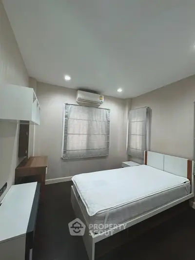 Spacious bedroom with modern furnishings and natural light, featuring a comfortable bed and sleek design.