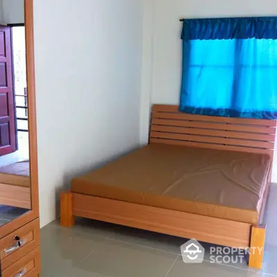 Cozy bedroom with minimalist wooden bed and matching side drawer, blue curtain accent, and tiled flooring, perfect for modern compact living.