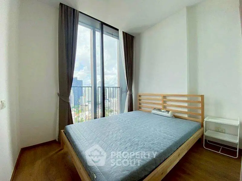 Spacious bedroom with large window offering stunning city views