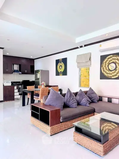Spacious modern living room with open kitchen, stylish decor, and natural light.