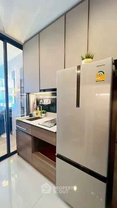 Modern kitchen with sleek cabinets and stainless steel fridge in a stylish apartment.