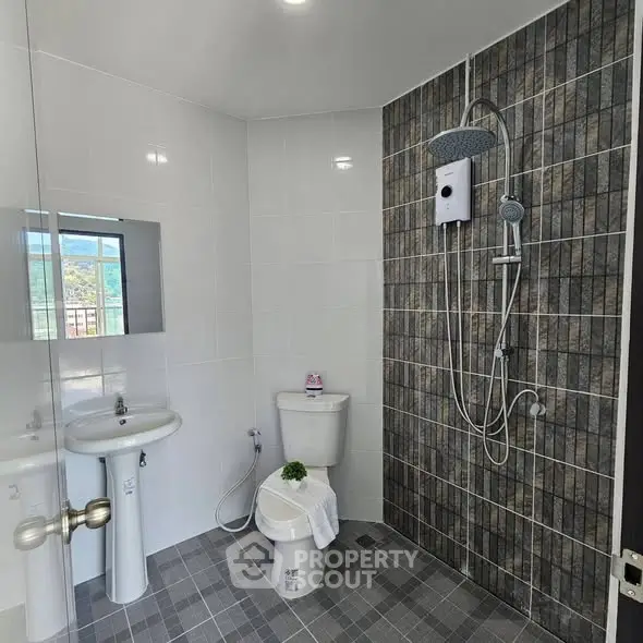 Modern bathroom with sleek shower and tiled walls, featuring a contemporary design.