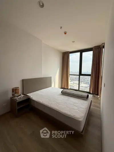 Modern bedroom with large window offering stunning city view and natural light.