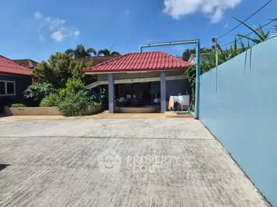 Charming single-story home with red roof and spacious driveway under clear blue sky.