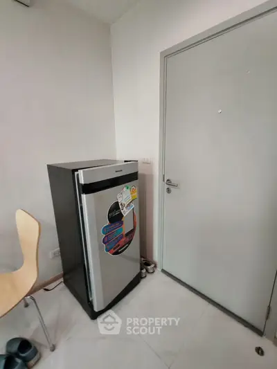 Compact kitchen corner with modern fridge and sleek chair