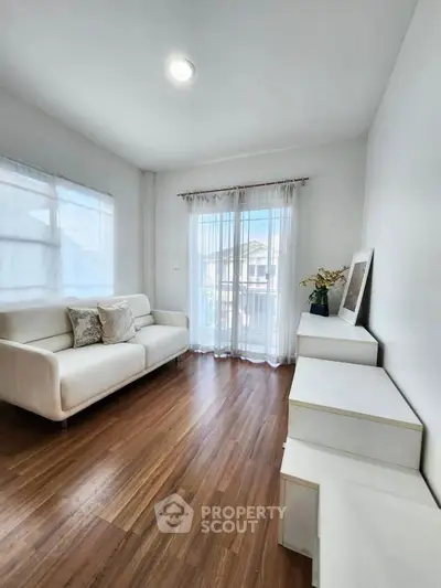 Bright and airy living room with modern white sofa and wooden flooring, perfect for relaxation.