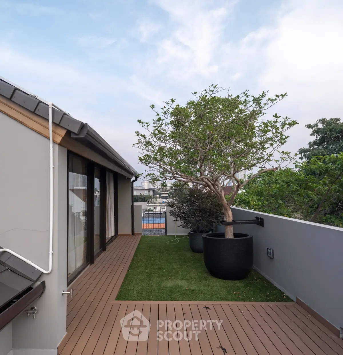 Modern rooftop terrace with wooden decking and potted plants, offering a serene outdoor space.