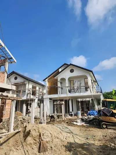 Newly constructed modern two-story houses with balconies under clear blue sky.
