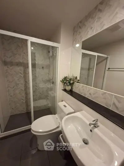 Modern bathroom with shower enclosure and elegant sink in a stylish apartment.