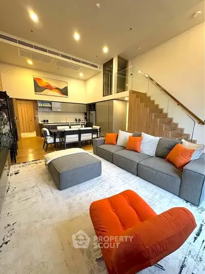 Modern living room with open kitchen and stylish staircase in luxury apartment.