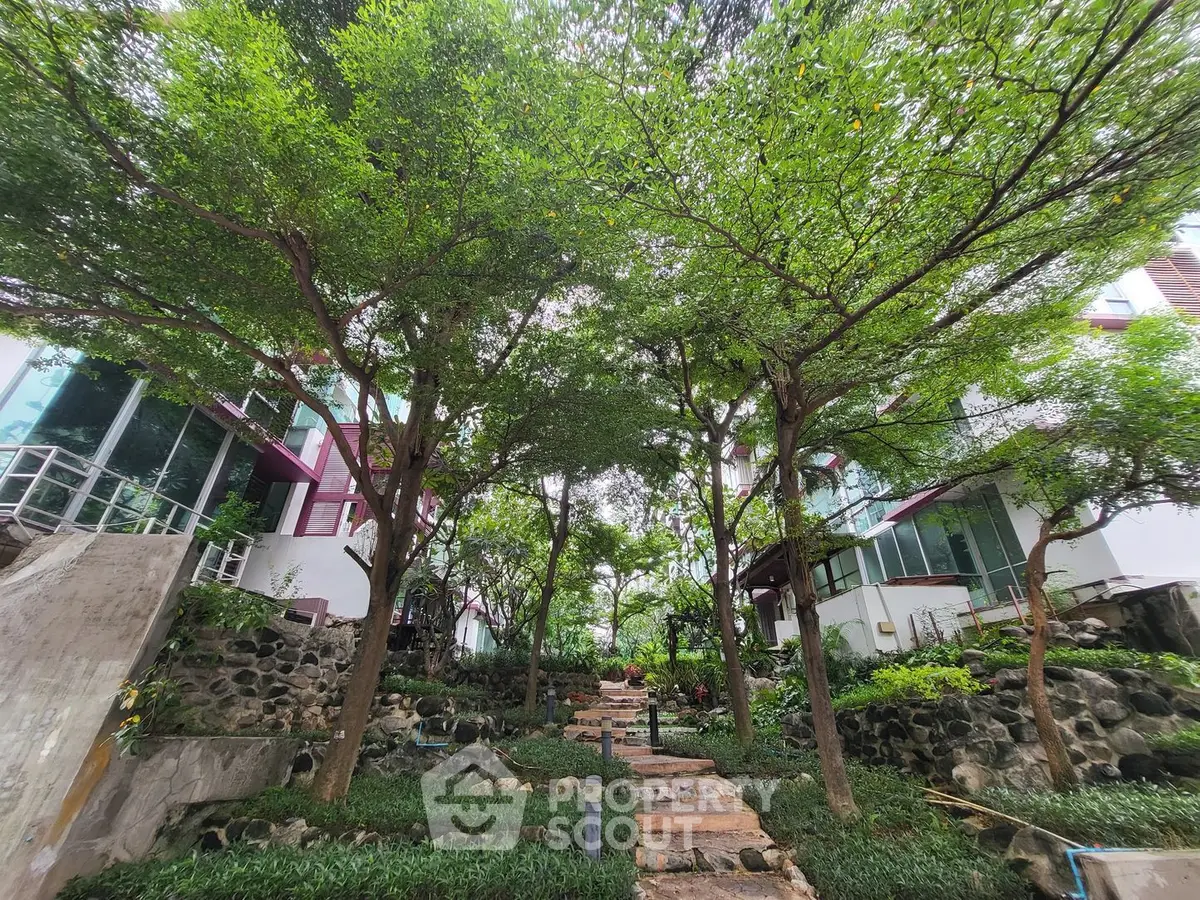 Lush garden pathway surrounded by modern architecture and greenery, offering serene outdoor living.