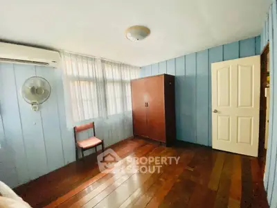 Cozy bedroom with wooden floors and blue panel walls, featuring a wardrobe and air conditioning.
