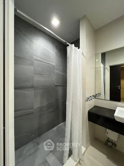 Modern bathroom with sleek shower and stylish vanity in contemporary home.