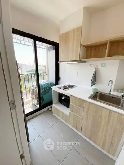 Modern kitchen with balcony access, featuring sleek cabinetry and a compact design, perfect for urban living.