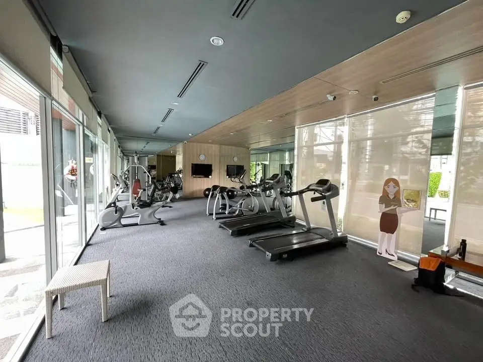 Spacious modern gym with state-of-the-art equipment and large windows for natural light.