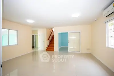 Spacious living room with staircase and large windows in modern home