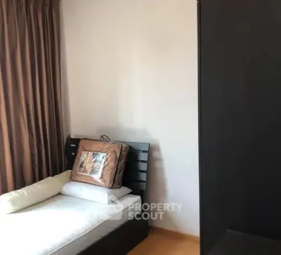 Cozy bedroom with single bed and dark wood furniture, ideal for minimalist living.