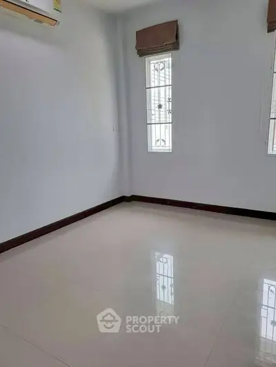 Spacious empty room with tiled flooring and natural light from windows.