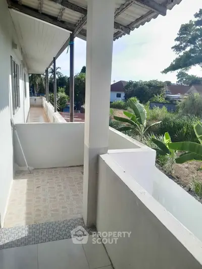 Charming balcony with serene garden view in a peaceful residential area.