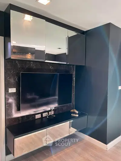 Modern living room with sleek black cabinetry and mounted TV, featuring elegant design and ample storage space.