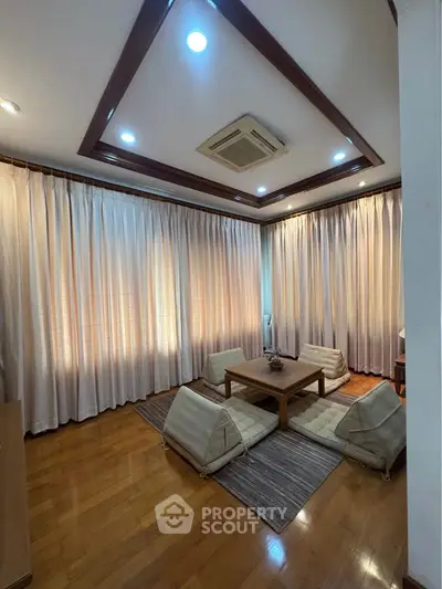Elegant living room with wooden flooring, cozy seating, and ambient lighting, perfect for relaxation.