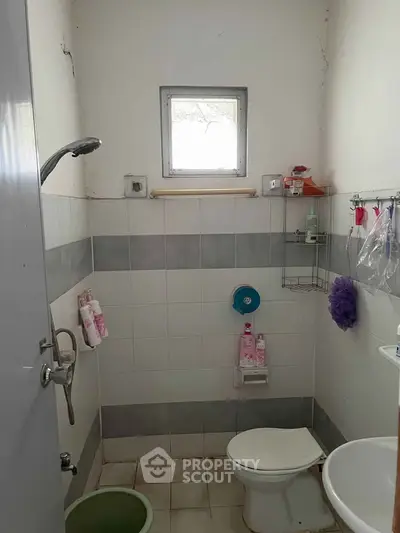 Compact bathroom with shower, toilet, and small window, ideal for efficient space use.
