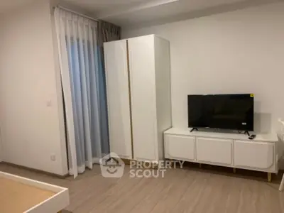 Modern bedroom with sleek wardrobe and TV unit, featuring minimalist design and neutral tones.