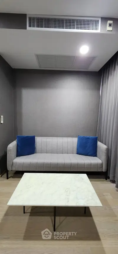 Modern living room with sleek gray sofa and marble coffee table, perfect for urban living.