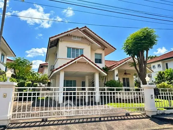 Charming two-story house with red-tiled roof and gated driveway in a serene neighborhood.