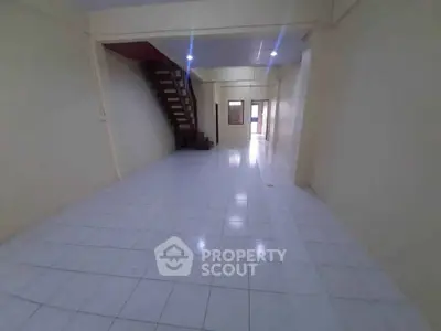 Spacious open-plan interior with tiled flooring and staircase, ideal for versatile living arrangements.