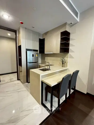 Modern kitchen with sleek design, featuring a compact island and stainless steel appliances.
