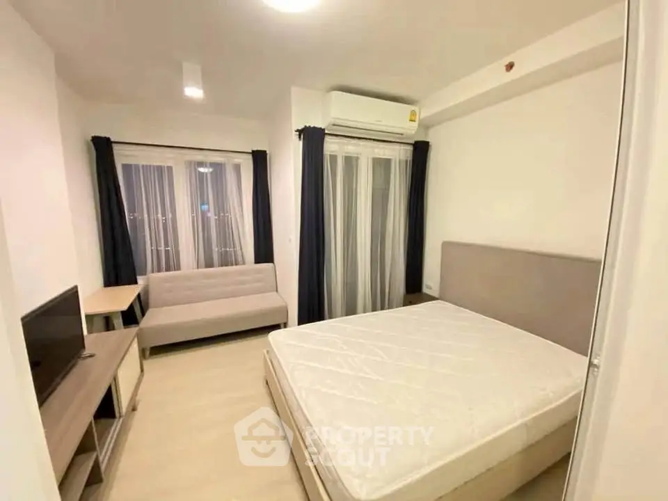 Modern bedroom with minimalist decor, featuring a cozy bed, sofa, and TV in a well-lit space.