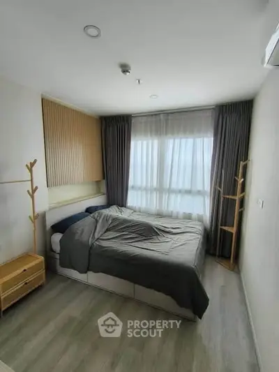 Modern bedroom with large window and stylish decor in a contemporary apartment.