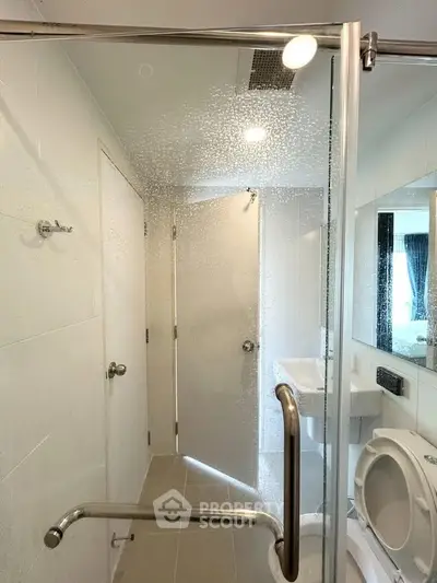 Modern bathroom with glass shower door and sleek fixtures in a contemporary apartment.