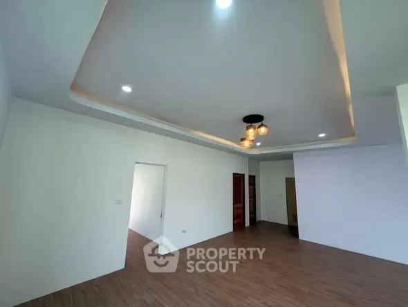 Spacious modern living room with elegant ceiling lights and wooden flooring