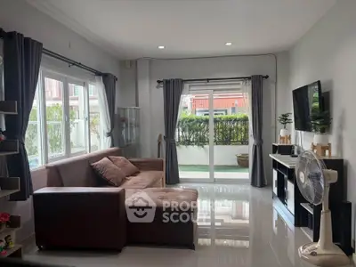 Spacious living room with modern decor and large windows offering natural light and garden view.