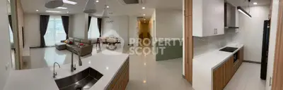 Spacious modern apartment with open kitchen and elegant living room, featuring sleek design and ample natural light.